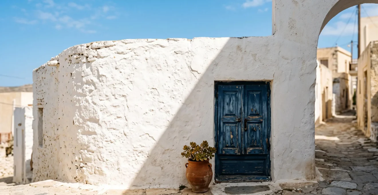 A sun-drenched whitewashed stone wall in a Mediterranean-style village, showing texture and brilliant light reflection